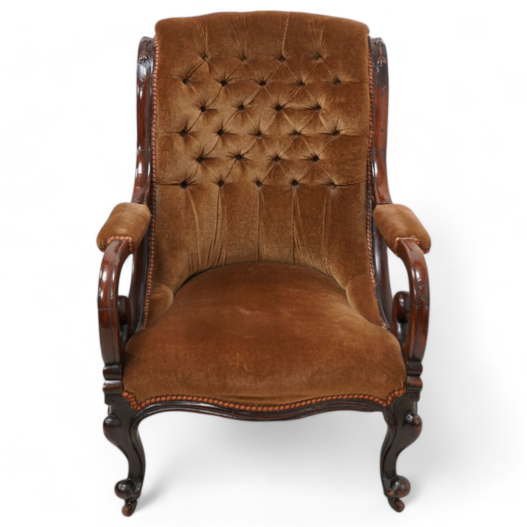 Victorian mahogany framed drawing room chair, scrolled back with bell-flower mouldings over scrolled arm terminals, upholstered in buttoned hazelnut brown fabric with sprung seat, cabriole supports on castors