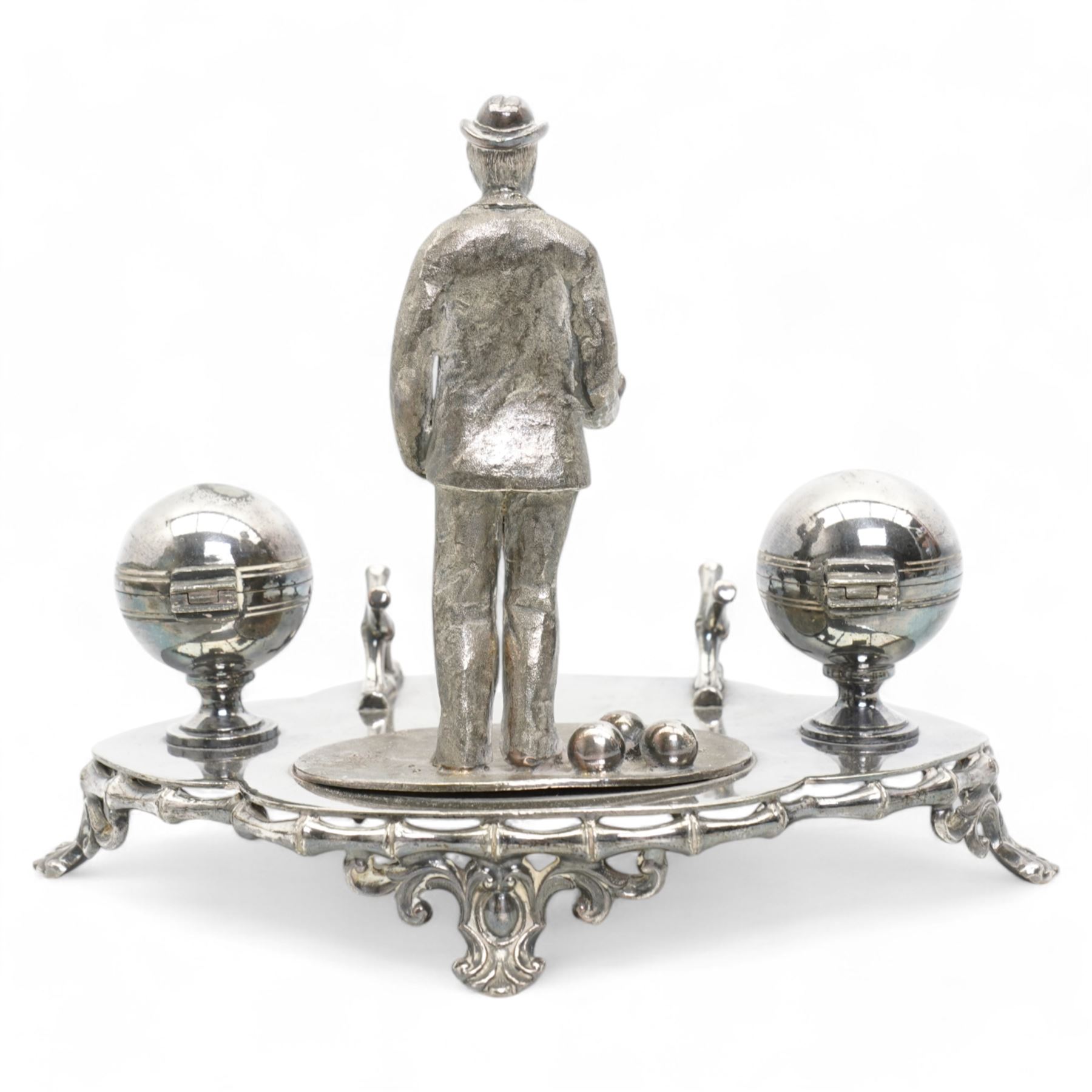 Victorian silver-plated inkstand by James Dixon & Sons, the quatrefoil base surmounted with a figure of a lawn bowler stood upon an oval grass base, with three lawn bowls by his feet, the inkwells formed as two bowls, each with hinged covers and silver-plated liners, bamboo moulded pen rest and gallery, supported by four pierced and splayed feet, L22cm x H17cm