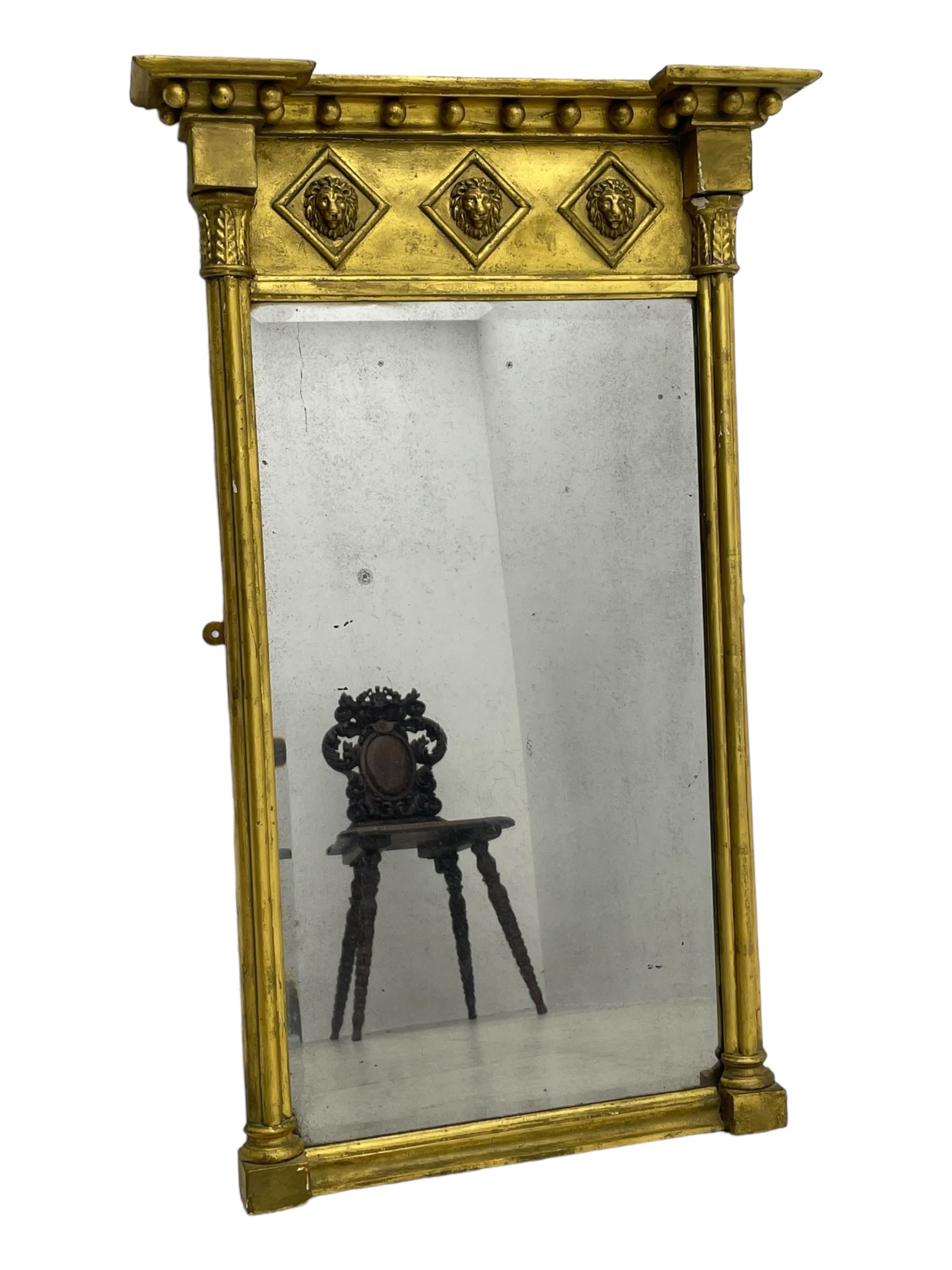 Regency giltwood and gesso pier mirror, projecting moulded cornice with globular mounts, the frieze decorated with three lion masks within lozenges, cluster column uprights with leaf decorated capitals, bevelled mirror plate