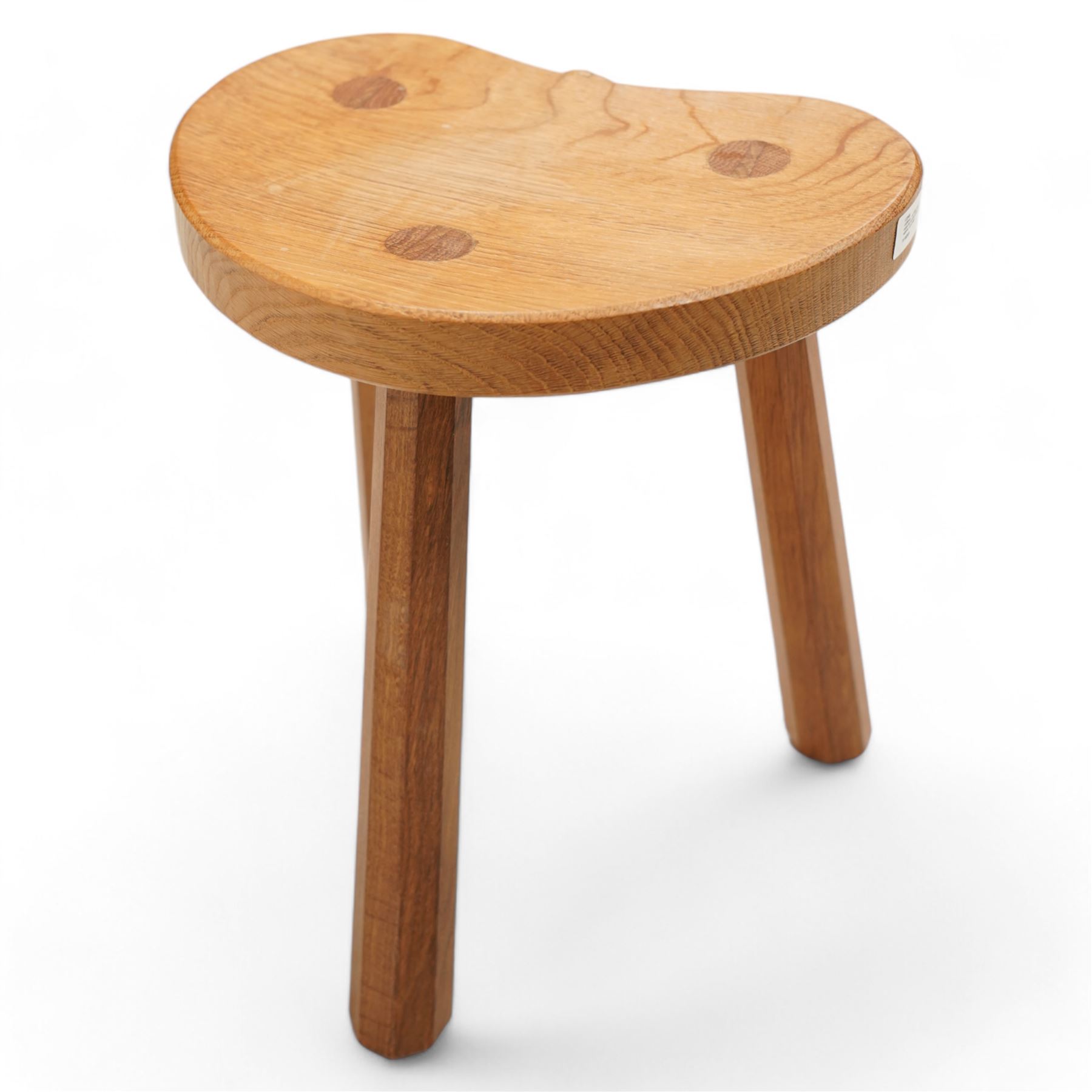 Rabbitman -  oak milking stool, dished kidney shaped top, on three tapered octagonal supports, carved with rabbit signature, by Peter Heap, Wetwang