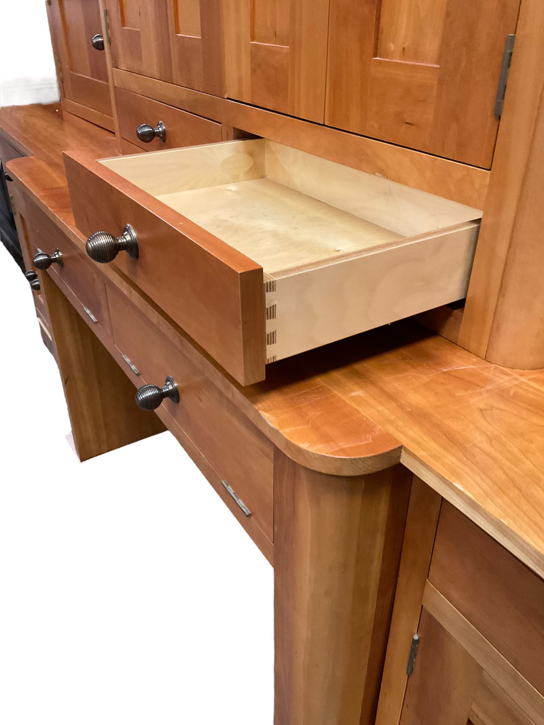 Large contemporary cherry wood break-front wall unit, the banded cornice over double cupboard with bifold doors and two drawers, flanked by four single cupboards, the base fitted with four drawers over four cupboards