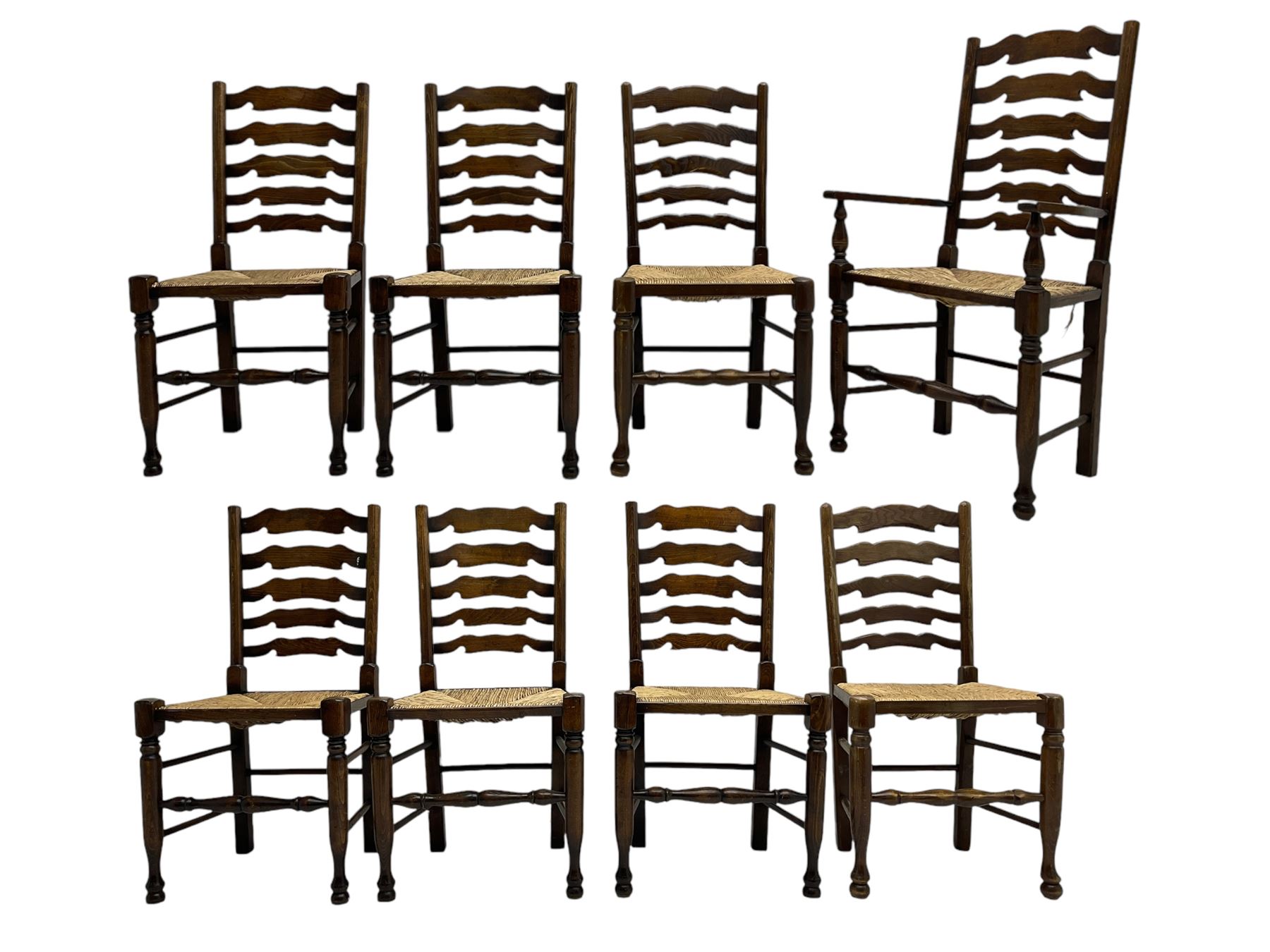 Matched set of eight (7+1) oak ladder back dining chairs, waved ladder back over rush seats, on turned supports joined by turned stretchers