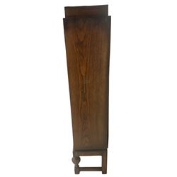 Edwardian oak bookcase, stepped top decorated with beading and stylised floral frieze, single astragal glazed door enclosing encyclopaedias and other books, on turned front feet united by plain stretchers 