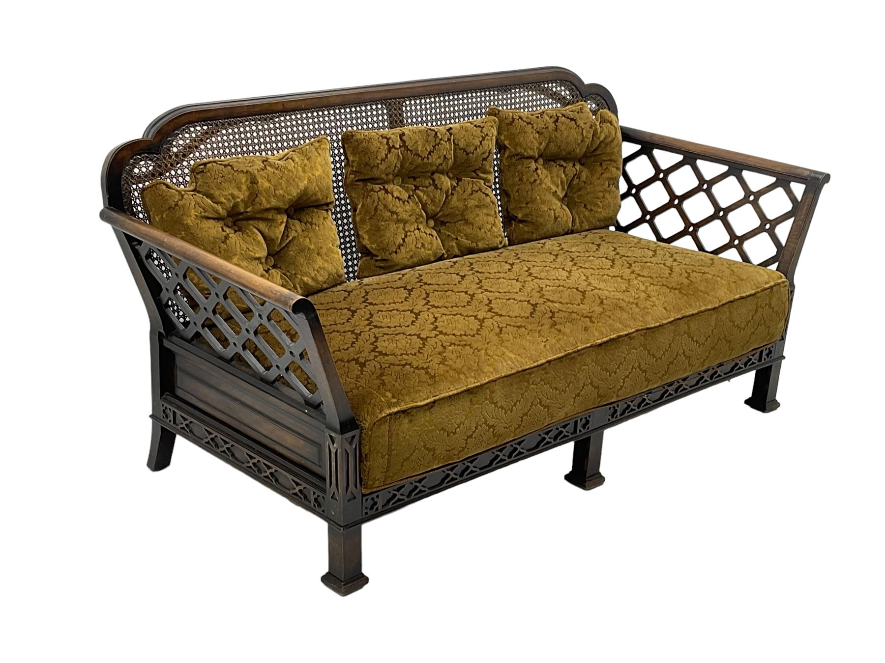 Early 20th century three-piece bergère suite - three seat sofa (W177cm, H82cm, D75cm); pair of matching armchairs (W84cm); single caned back with 'cock-pen' panelled arms, upholstered in foliate pattern fabric, blind fretwork lower frieze over square feet 