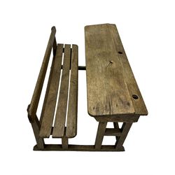 Victorian child's pine double school desk, the writing surface with two inkwells and two shelves underneath, integrated slatted bench seat raised on supports united by stretcher 