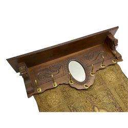 Late 20th century oak wall hanging coat rack, central bevelled oval mirror in foliate carved surround, decorated with S-scrolls and lion masks, fitted with needlework hanging 