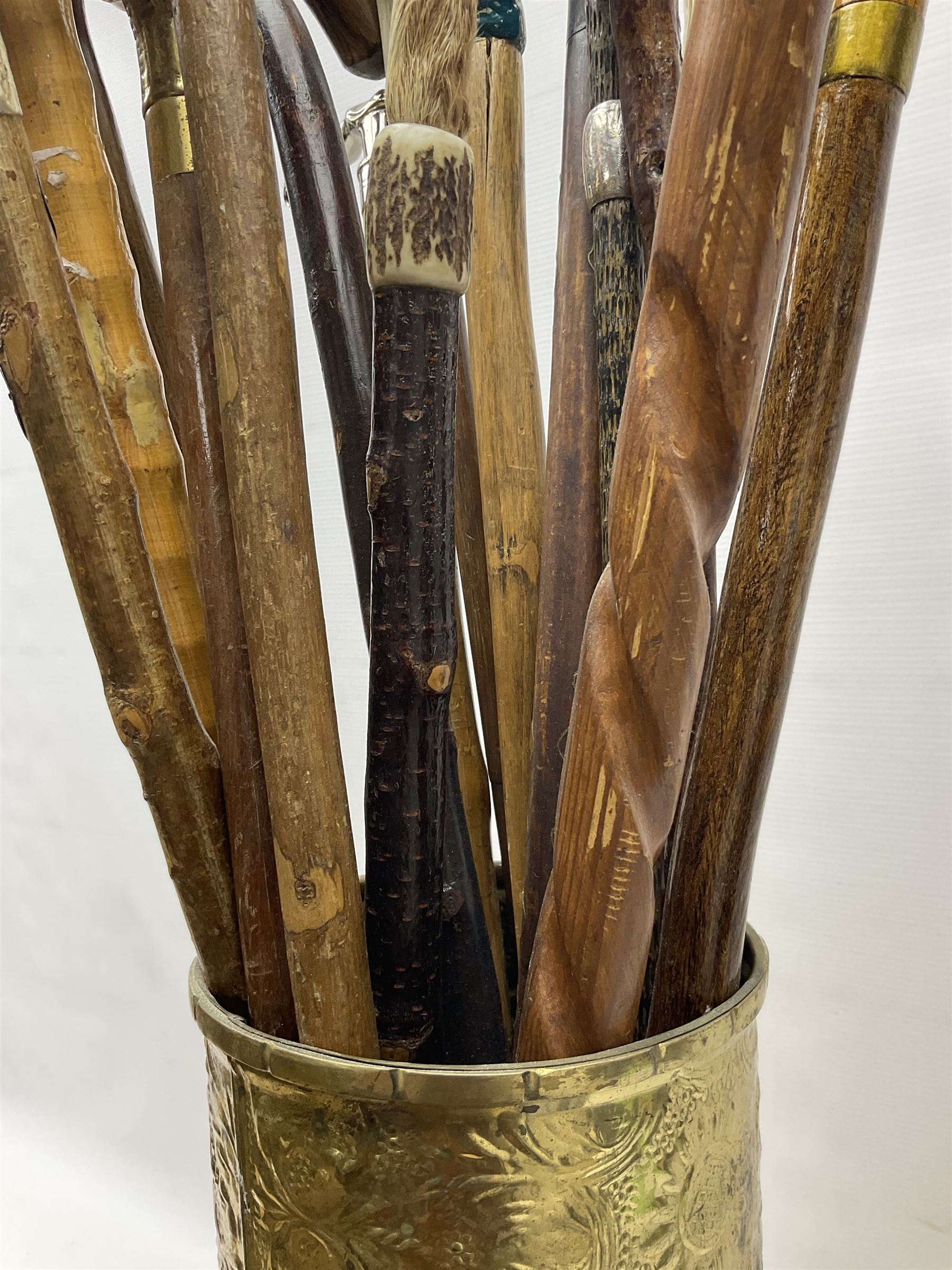 Oak barley twist stick stand, with a collection of walking sticks including examples with carved pommels, horn handles, silver collar etc, together with brass stick stand 