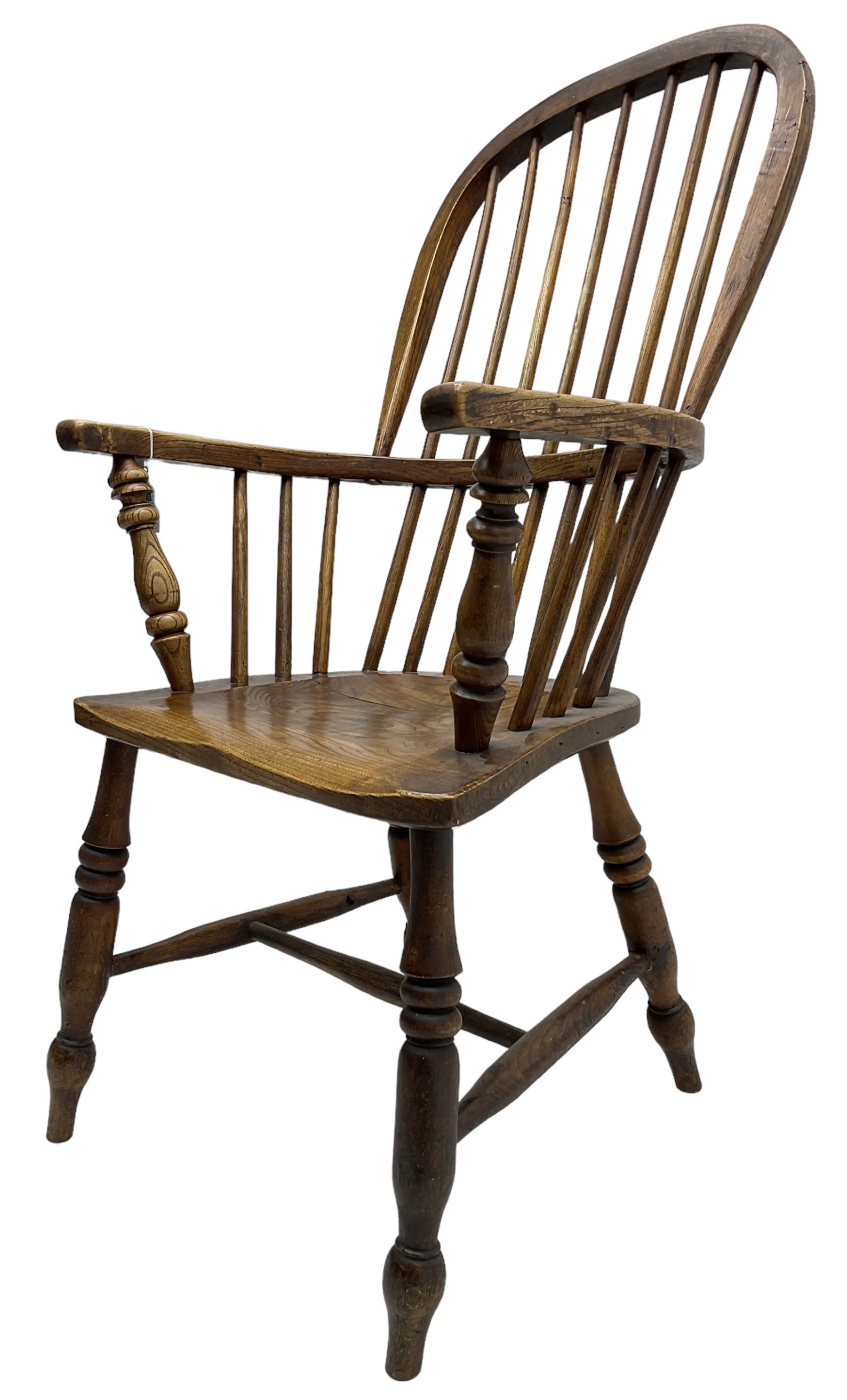 Early 19th century elm Windsor chair, high hoop and stick back over shaped saddle seat, raised on ring turned supports united by H-stretcher