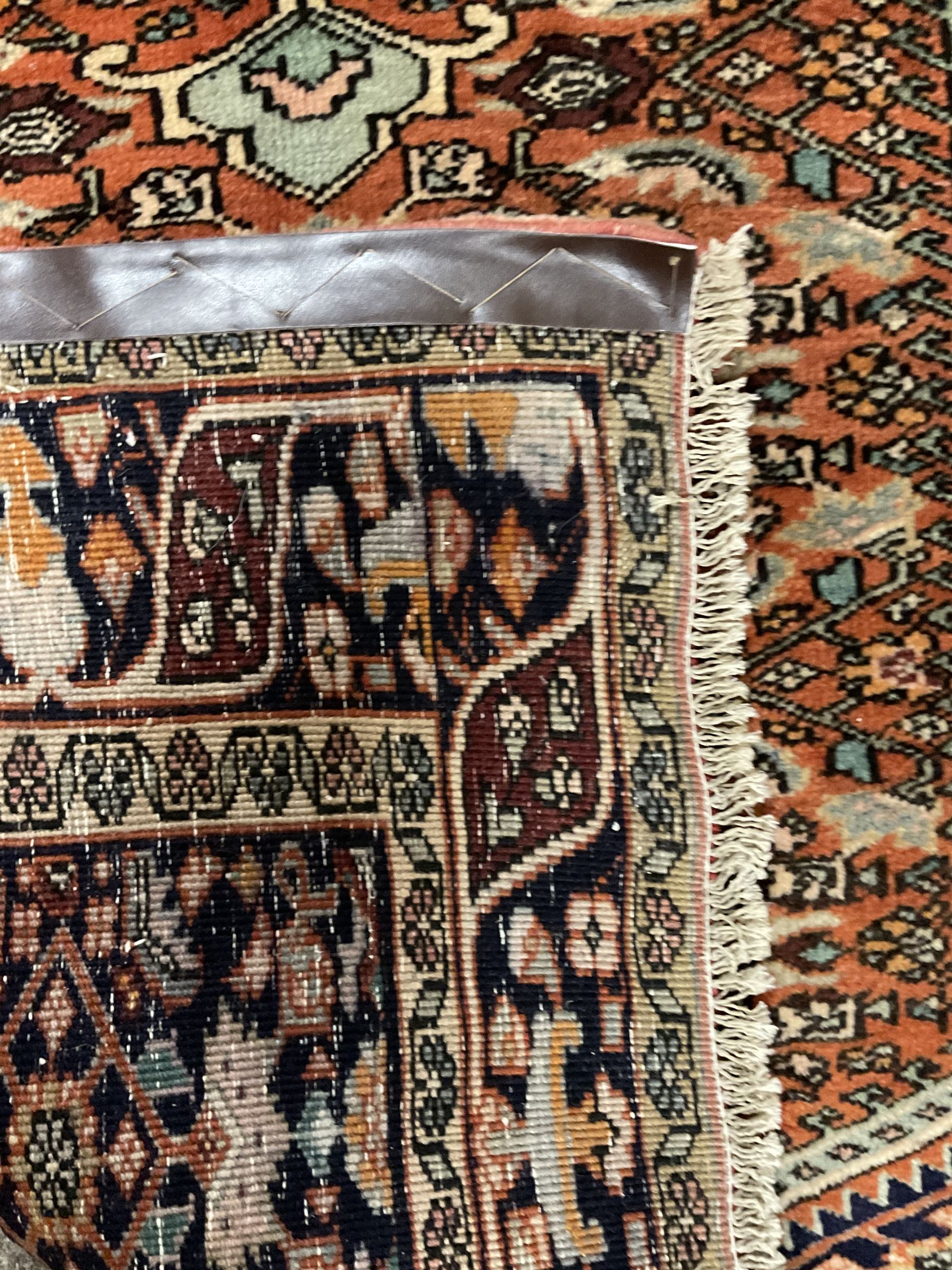 North West Persian Bidjar rug, orange peach ground extended field on indigo ground, decorated with floral Herati motifs, repeating waved border decorated with stylised plant motifs