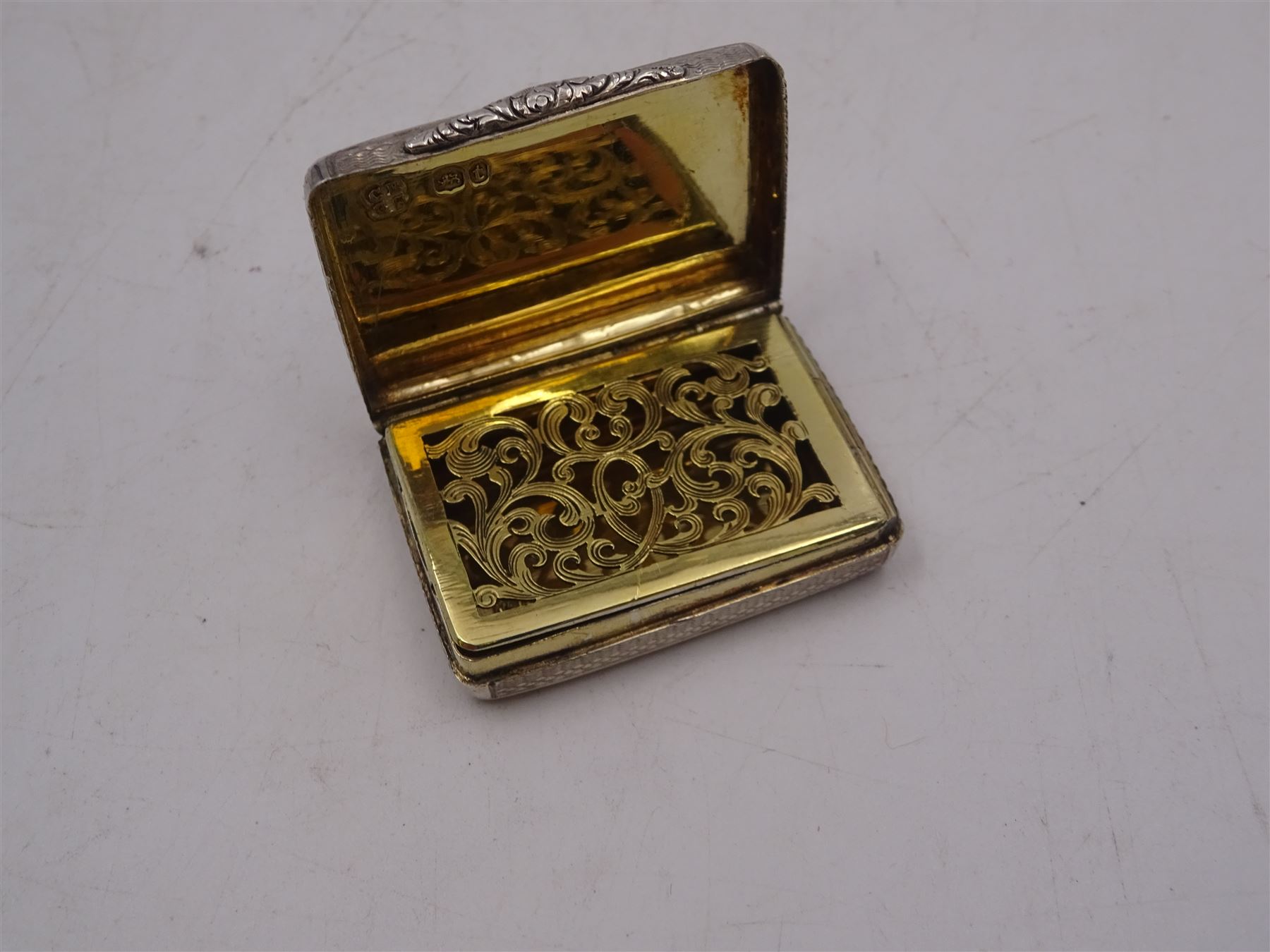 William IV silver vinaigrette, of rectangular form, with engine turned decoration throughout, chased scrolling borders and engraved cartouche to hinged cover, opening to reveal gilt interior with typical pierced cover, hallmarked Charles Reily & George Storer, London 1834, W3.7cm