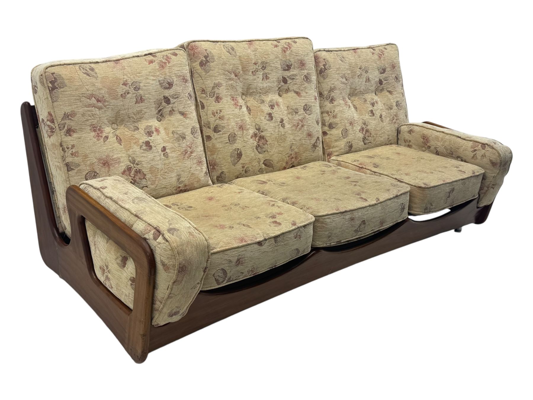 Mid-20th century three-seat sofa with floral patterned upholstery, supported by a sculpted teakwood frame with curved cutout detailing, loose cushioned back and seat, on tubular metal feet