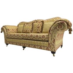 Steed Upholstery Ltd. - 'Lincoln' three-seat sofa upholstered in gold 'Olympia' floral pattern corded and tasselled fabric, together with scatter cushions and arm covers, on turned feet with brass castors