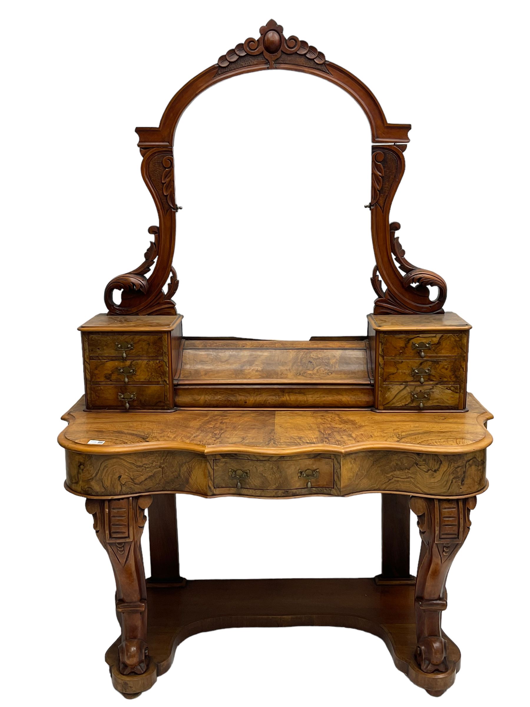 19th century figured walnut dressing table, the raised bevelled mirror back in carved foliage frame with scrolled terminals, fitted with central hinged compartment flanked by small trinket drawers, serpentine moulded top over single frieze drawer, on cabriole supports united by a platform base