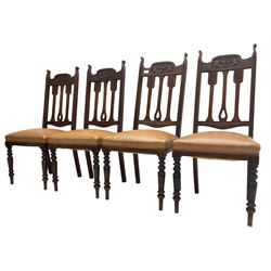 Set of four Edwardian walnut dining chairs, foliate carved high back over sprung seat upholstered in tan faux leather, raised on turned supports