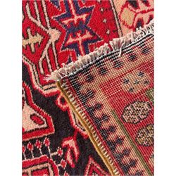 Persian Hamadan indigo and crimson ground rug, the field filled with three shaped medallions, overall geometric design, decorated with sandikli and hac motifs, geometric main border with repeating hooked motifs, within guard stripes decorated with small flower heads, outer crenelated fence band 