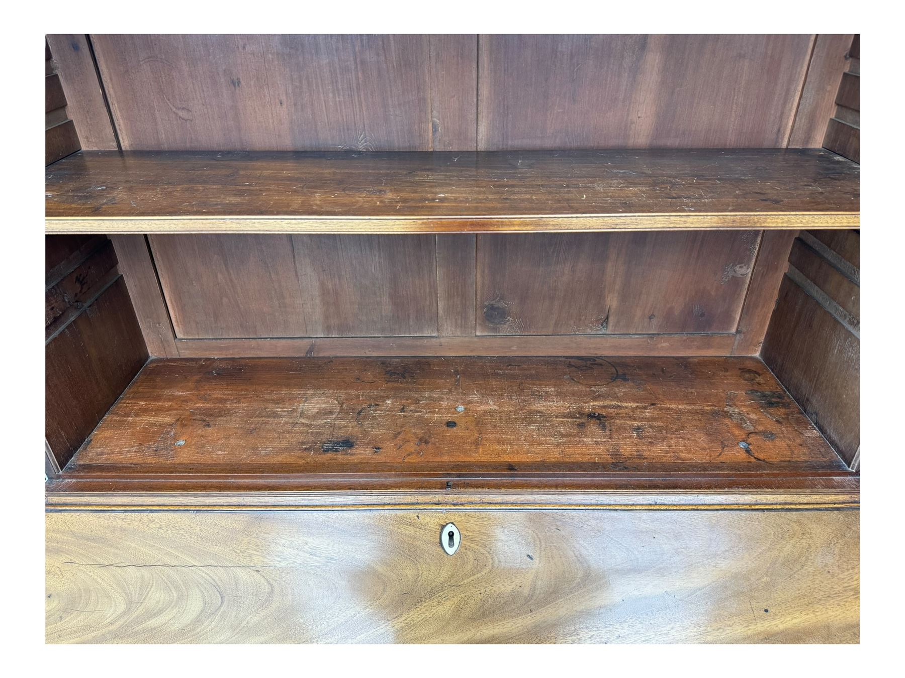 Early 19th century mahogany bureau bookcase, the projecting cornice over two Gothic-style astragal glazed doors enclosing two adjustable shelves, sloped hinged lid enclosing fitted interior and felt inset, four graduating drawers, on bracket feet