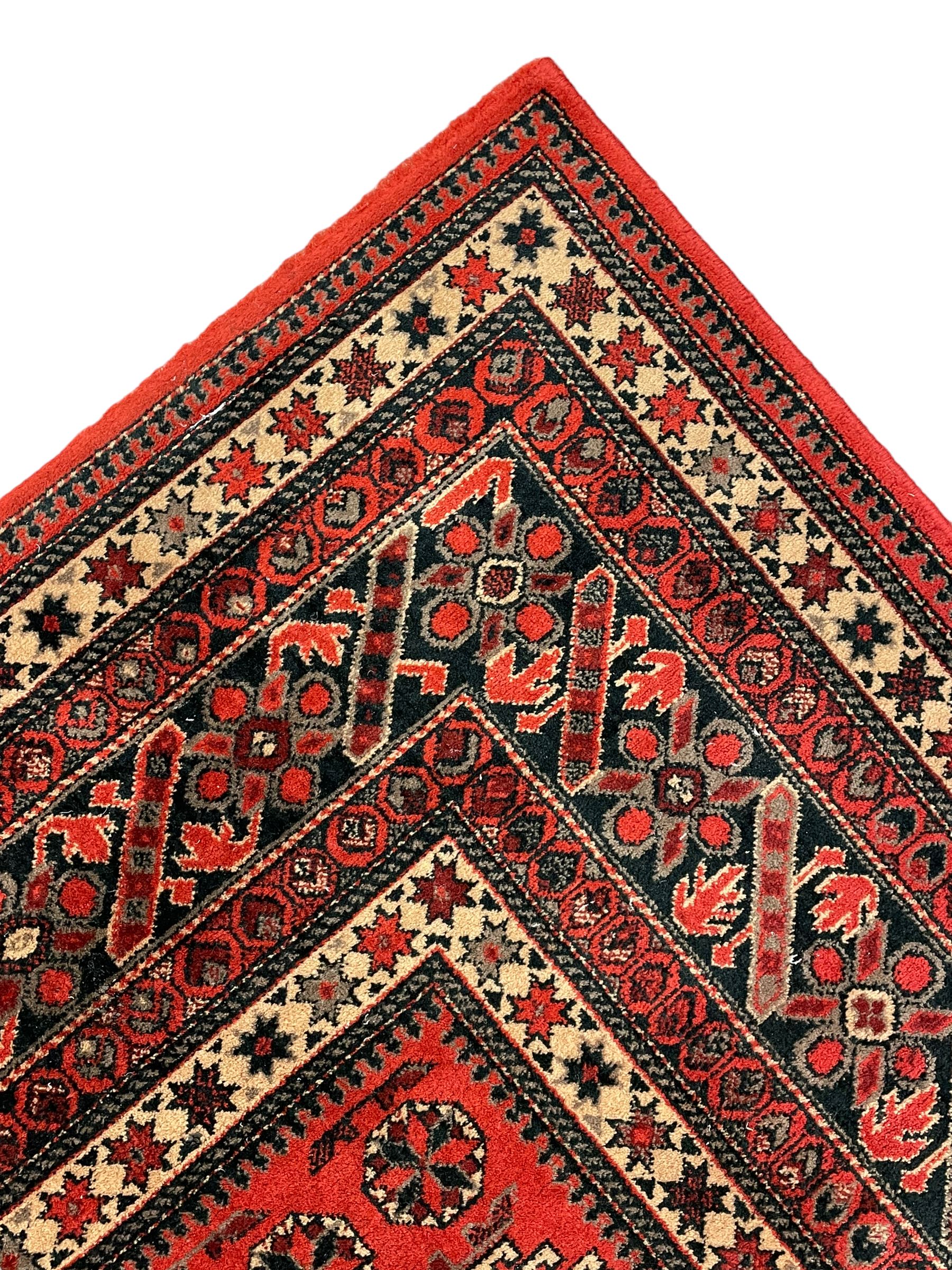 Persian design red ground rug, the field decorated with geometric motifs, repeating multiple band border 