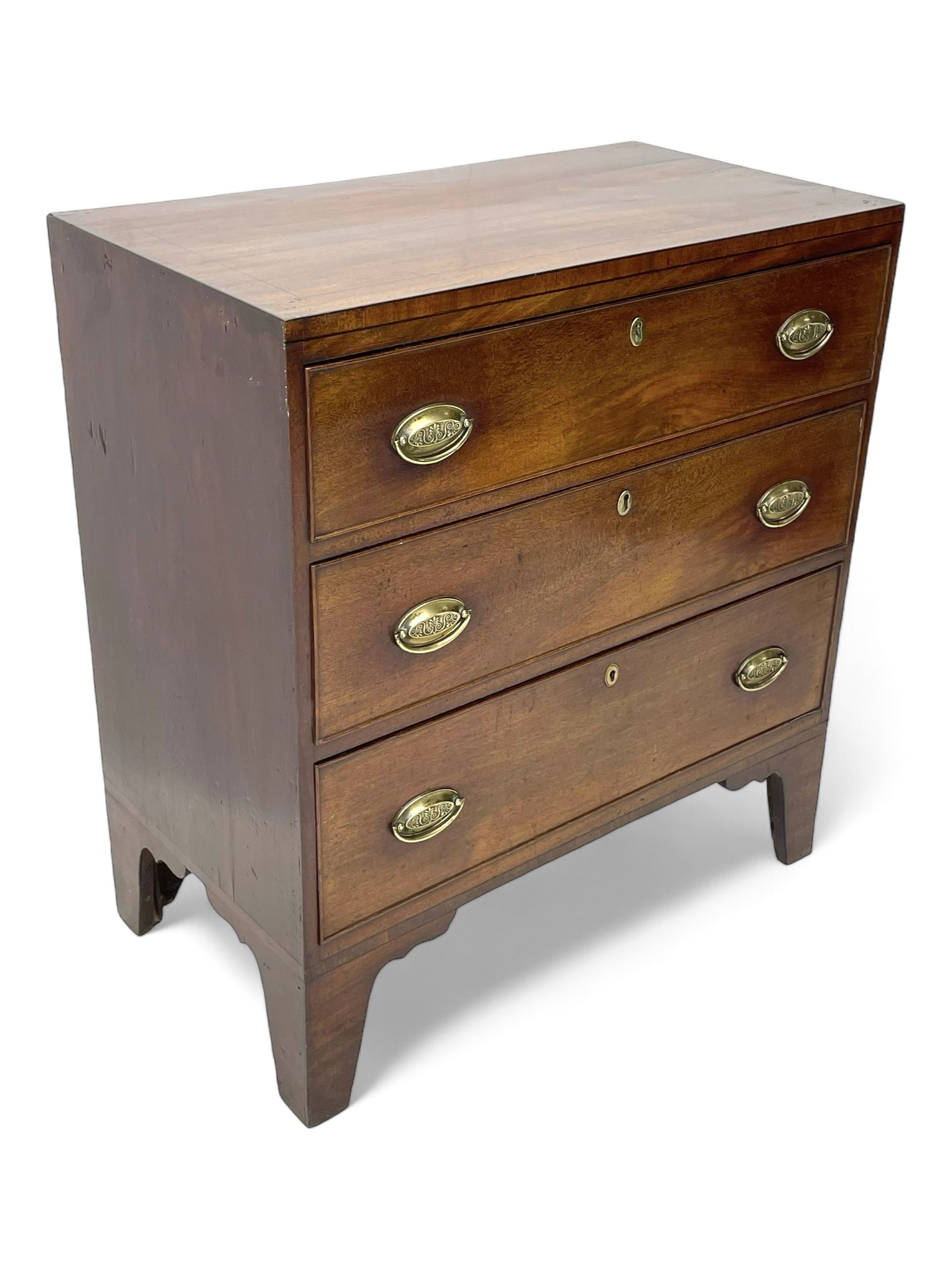 George III mahogany chest, rectangular ebony strung top, fitted with three graduating cock-beaded drawers with oval pressed brass handle plates and demi-lune handles, on tall bracket feet 