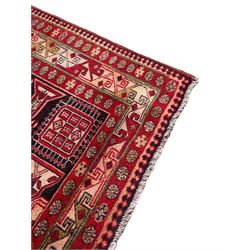 Persian Hamadan indigo and crimson ground rug, the field filled with three shaped medallions, overall geometric design, decorated with sandikli and hac motifs, geometric main border with repeating hooked motifs, within guard stripes decorated with small flower heads, outer crenelated fence band 