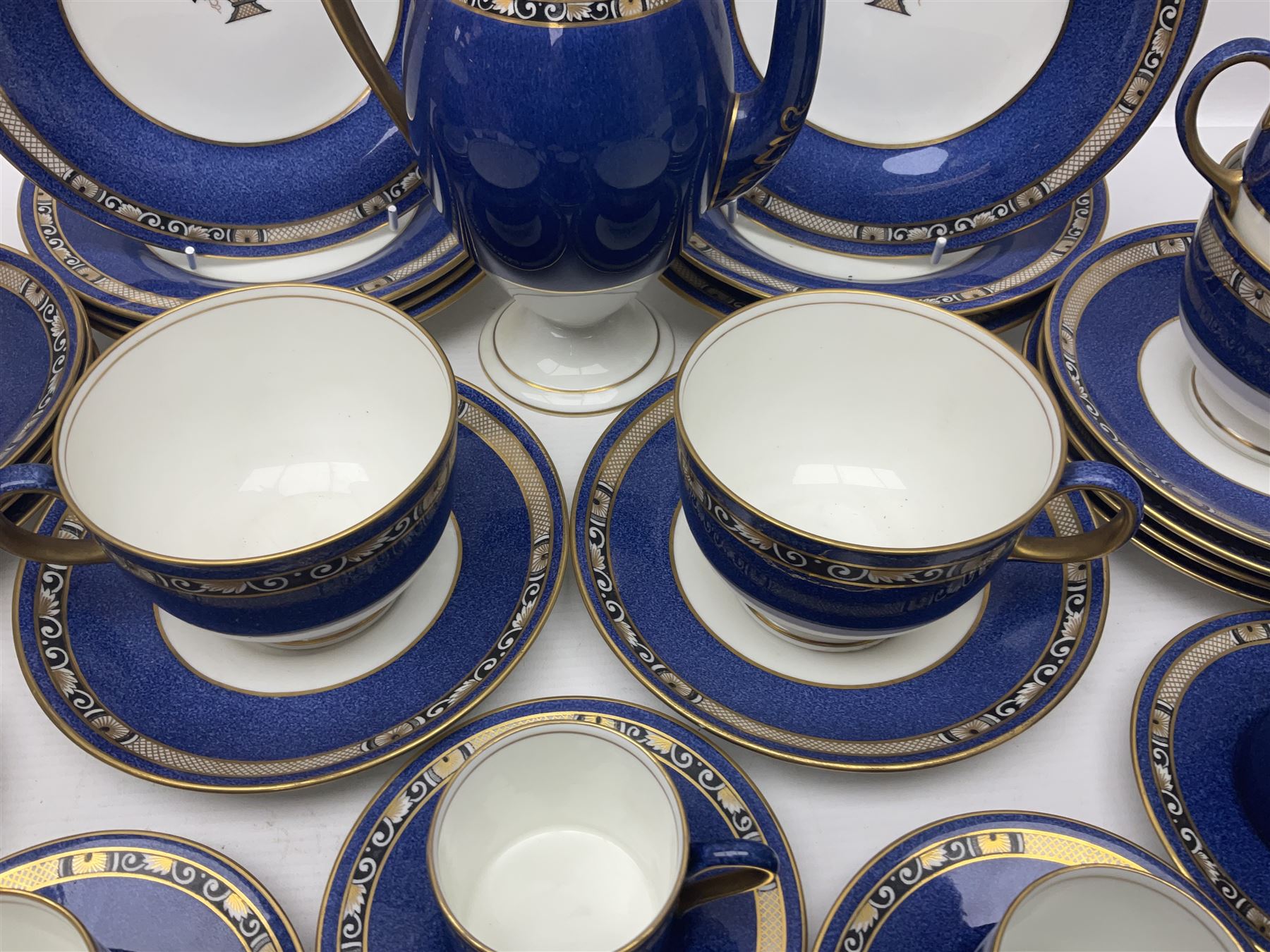 Wedgwood part tea and coffee service, comprising coffee pot, six coffee cans with five saucers, seven teacups with ten saucers and seven side plates, each decorated with floral bouquet to centre, in a gilt and speckled blue border, pattern x9933, with printed mark beneath