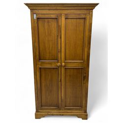 Hardwood double wardrobe, enclosed by two panelled doors, on bracket feet 