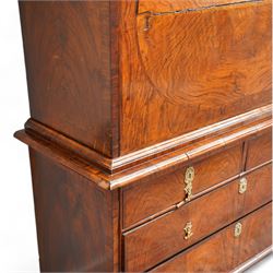 George II figured walnut escritoire, projecting moulded cornice over cavetto frieze with drawer, figured fall front revealing pigeonholes, a combination of drawers, central double cupboard and hidden drawers, fitted with two short and two long drawers, cast gilt metal escutcheons and drop handles, on turned feet 