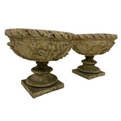 Pair of composite stone garden urn planters, acanthus leaf garland rim over foliate decorated body, stepped foot on square base