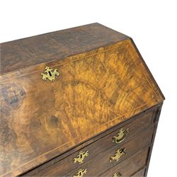 George I figured walnut bureau, hinged fall front enclosing drawers, pigeon holes and slide revealing storage well, fitted with four long cock-beaded and graduating drawers, shaped brass handle plates and escutcheons, on turned bun feet 