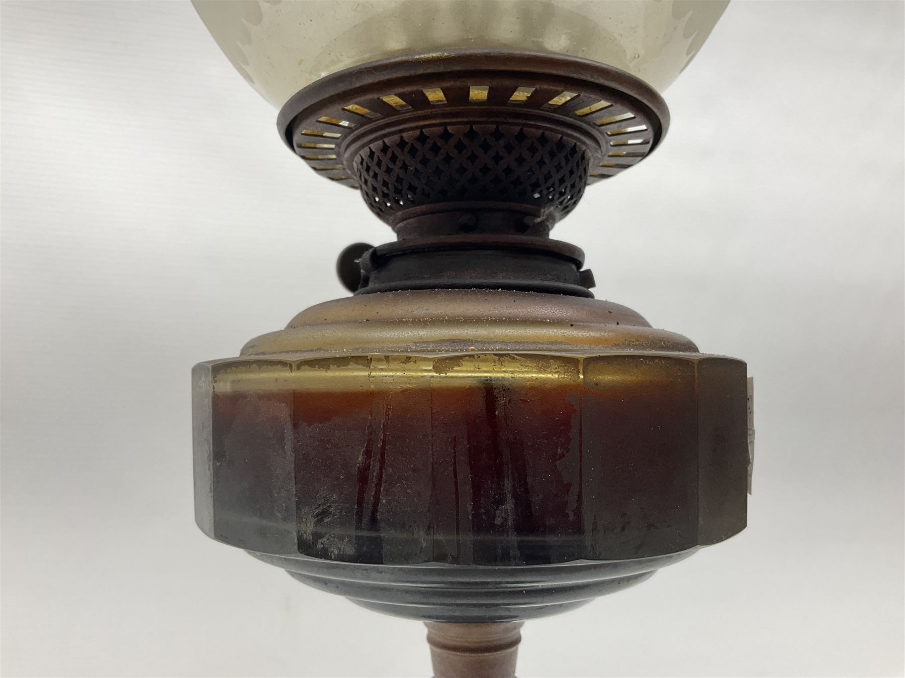 Victorian oil lamp, the faceted reservoir upon embossed copper stem and stepped circular ceramic base, with etched floral glass shade