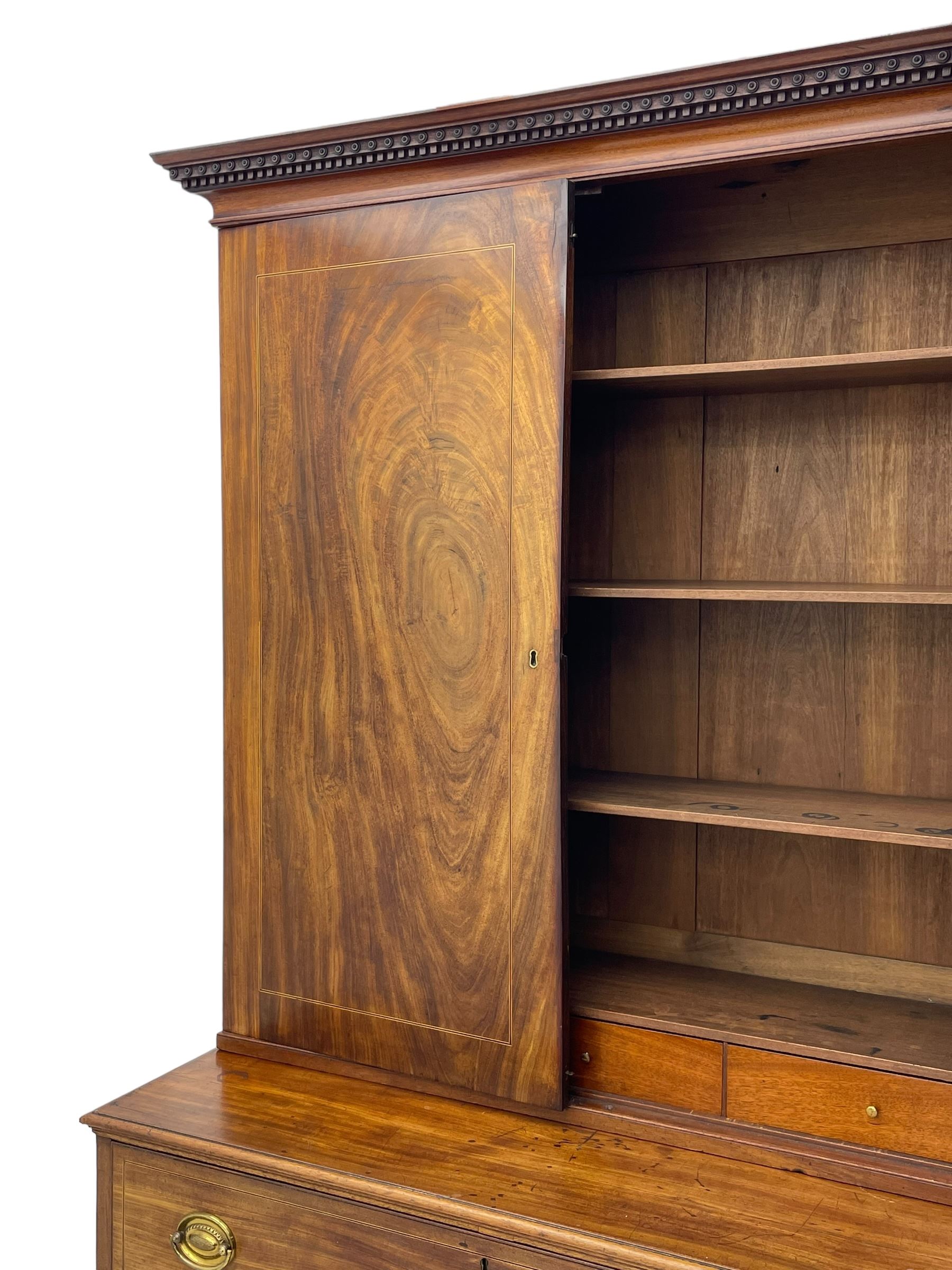 George III figured mahogany secretaire bookcase, projecting moulded dentil cornice decorated with single row of roundels, two figured mahogany doors with boxwood and ebony stringing enclosing three adjustable shelves and three drawers, moulded rectangular top over four long scratch-moulded drawers, the top secretaire drawer with fall front enclosing small drawers, pigeon holes and inset writing surface, shaped apron with bracket feet