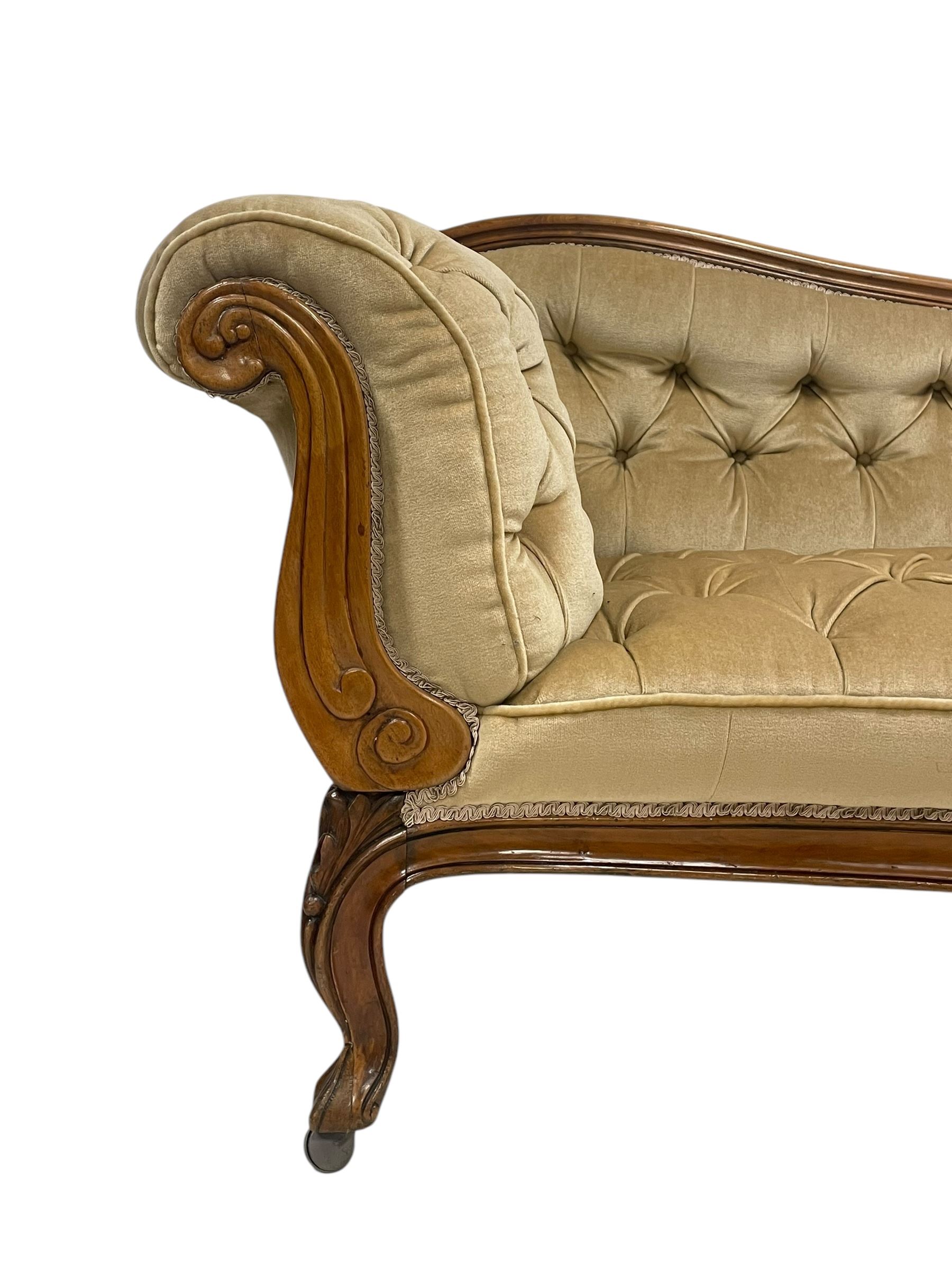 19th century walnut framed chaise longue, shaped back over scrolled arms decorated with moulded curling acanthus carvings, upholstered in deep buttoned champagne fabric, raised on cabriole supports with applied floral carved decoration, on castors