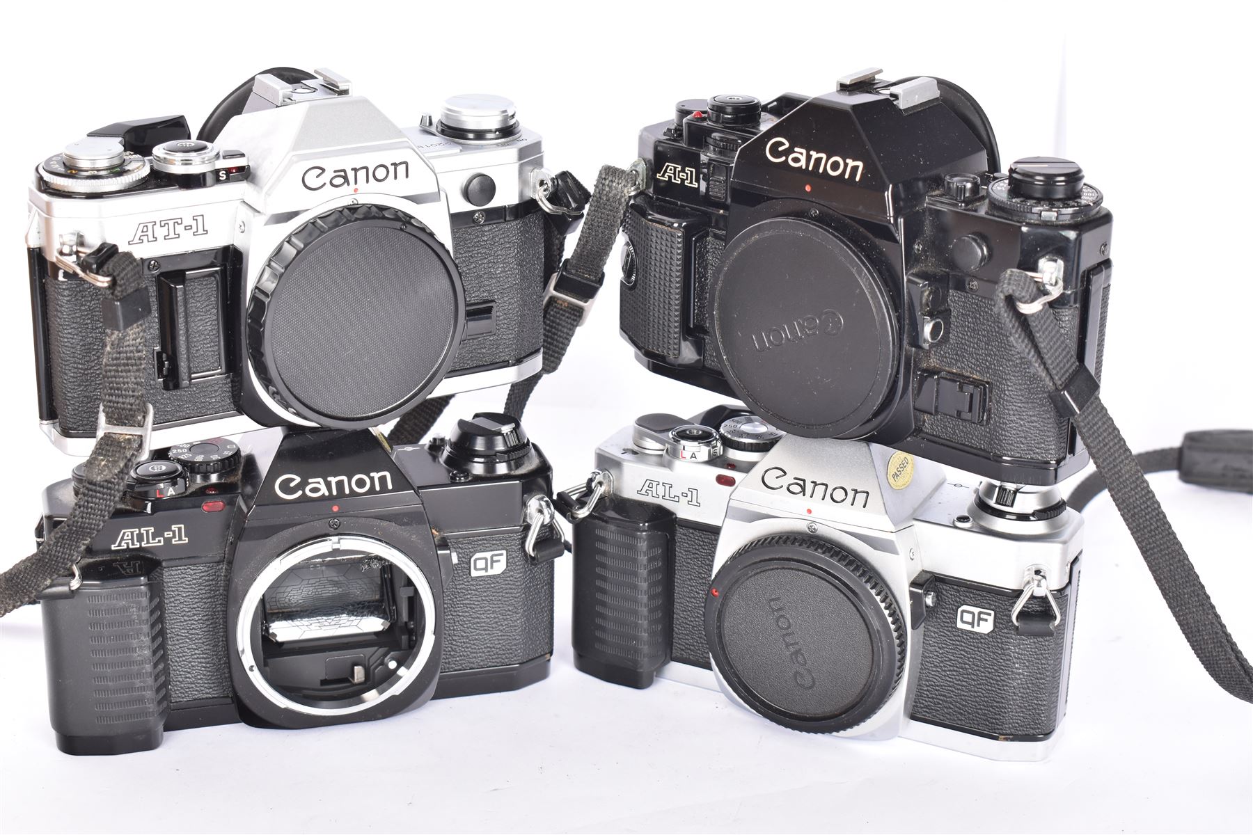 Four Canon SLR camera bodies, to include AT-1 in black and silver finish, serial no. 220197, A-1 in black, serial no. 508829, ad two AL-1 bodies, one black and one silver and black, serial nos. 1102614 & 3043913