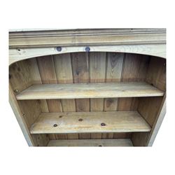 Pine open bookcase, projecting moulded cornice over arched frieze, fitted with four adjustable shelves, on plinth base