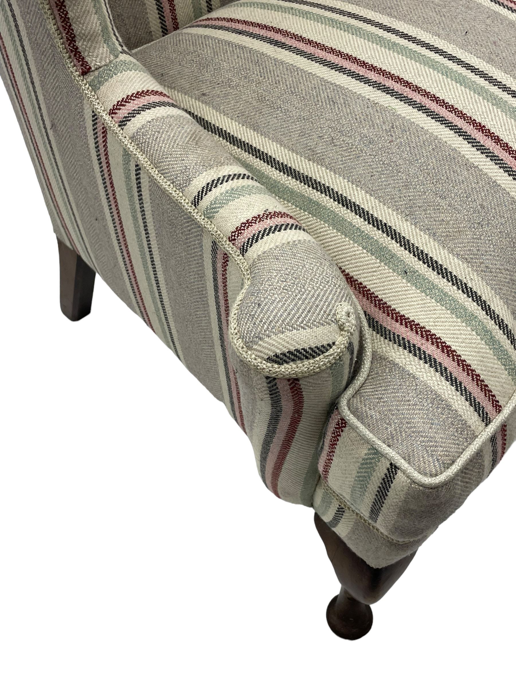 Georgian design hardwood-framed wingback armchair, curved wingback terminating to curved and rolled arms, upholstered in striped fabric with loose seat cushion, on cabriole front feet 