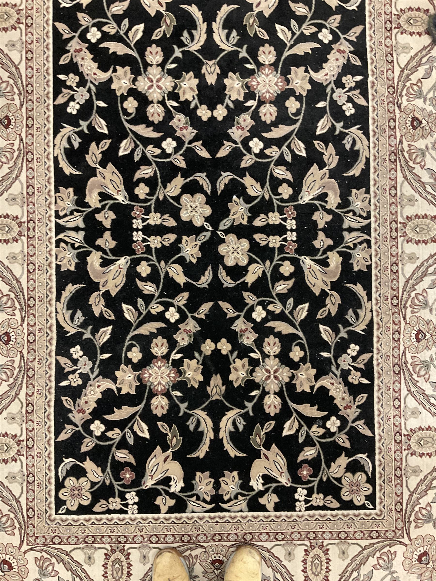 Persian design dark indigo ground rug, the field decorated with trailing branches and foliate motifs, repeating scrolling border with stylised plant motifs