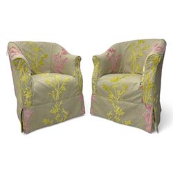 Pair of tub-shaped armchairs, mahogany frame loosely covered by branching floral pattern cover in pink and  yellow hues, skirted base, on concealed splayed rear and tapered front supports