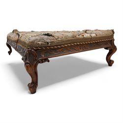 Victorian walnut low stool, rectangular form with needlework cover, the frieze rails carved with trailing foliate decoration, on cabriole feet with scroll carved terminals 