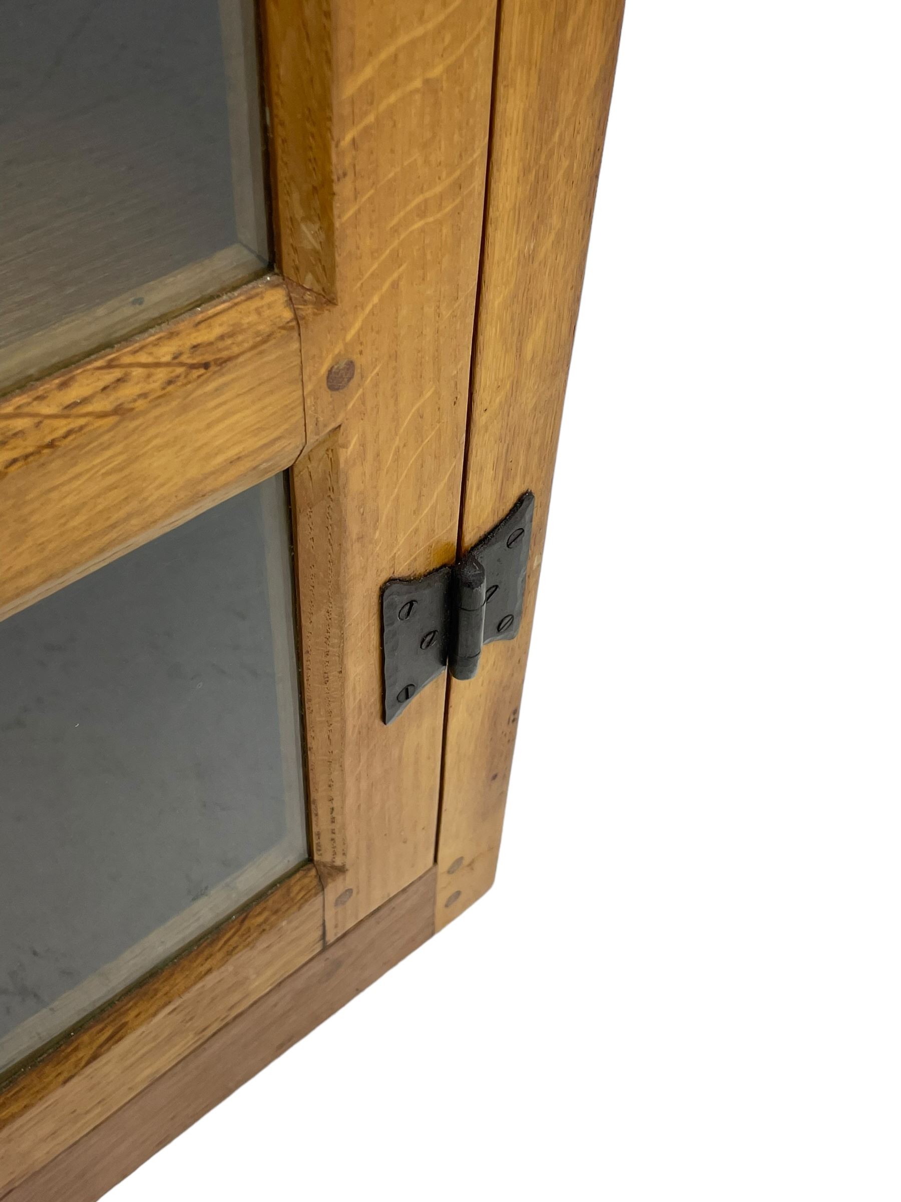 Rabbitman - oak corner cabinet, astragal glazed door enclosing three internal shelves, panelled upright corners, fitted with wrought metal hinges and latch, carved with rabbit signature, by Peter Heap, Wetwang 