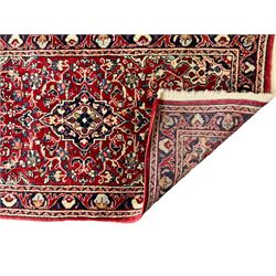 Persian crimson ground rug or mat, field decorated with central medallion and all-over scrolling floral motifs, border with repeating palmettes