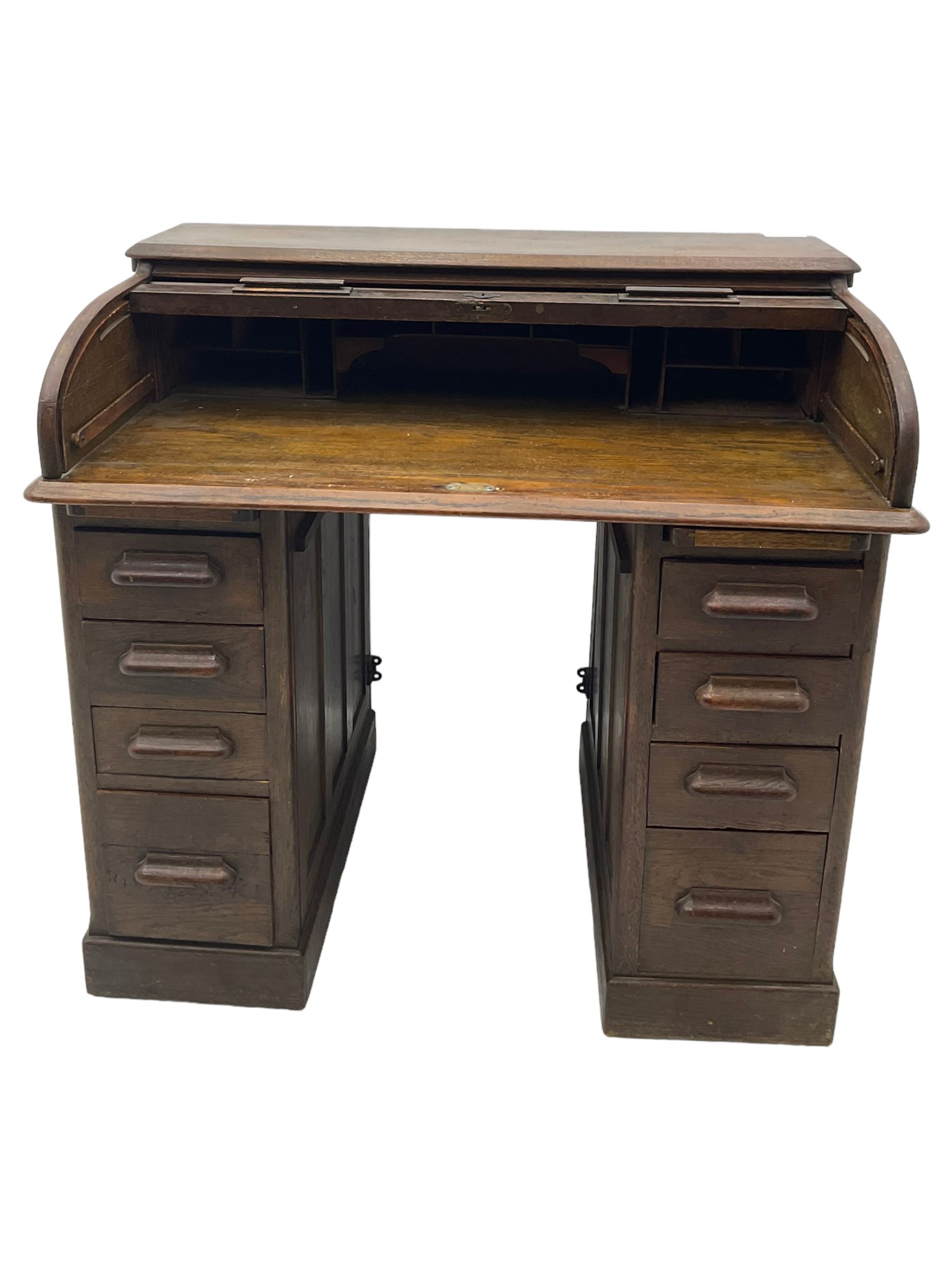 Early 20th century oak twin pedestal roll top desk, tambour roll enclosing fitted interior, each pedestal fitted with four drawers and slide, on plinth base 