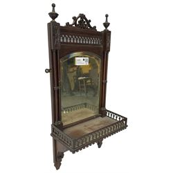 Early 20th century mahogany hall mirror with shelf, pierced pediment flanked by turned finials, the bevelled mirror plate enclosed by turned upright pillars, the shelf with fret work gallery, pierced lattice work lower panel 