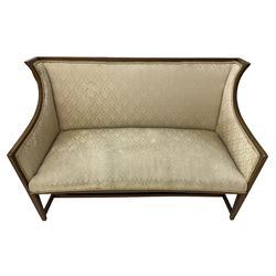Edwardian mahogany framed two-seat sofa, curved wingback frame with satinwood banding, upholstered in beige fabric, on square tapering supports united by H-stretcher 