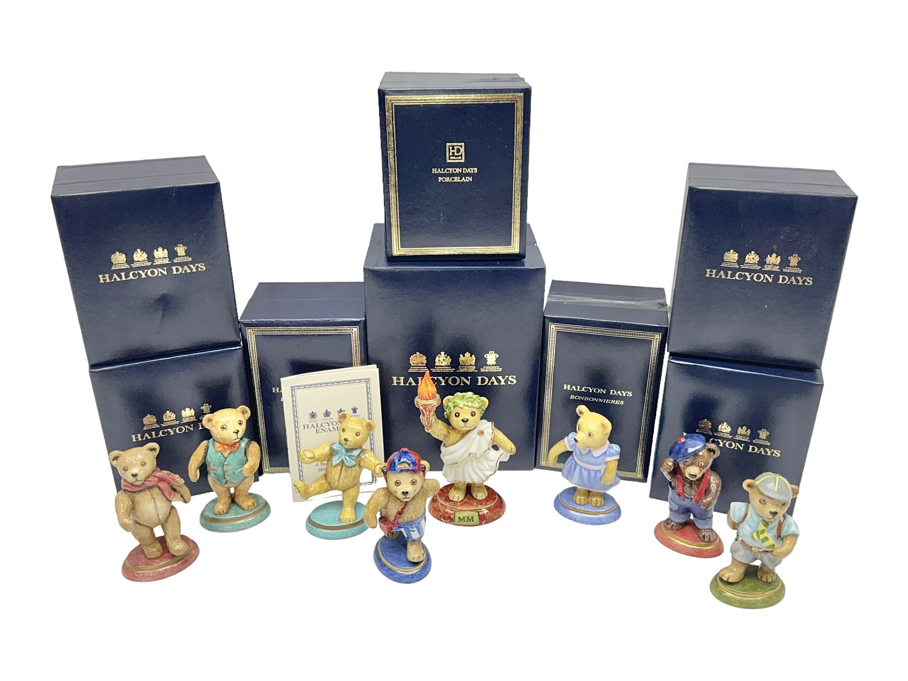 Eight Halcyon Days Teddy Bear of the Year figures, from 1993 to 2000, including one example modelled as a bear in Greek dress carrying a torch, one example modelled as a schoolboy and one example in a blue dress, all boxed 