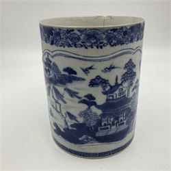 Two large 18th century Chinese blue and white tankards, each of cylindrical form, the first example with foliate mounted strap handle, the body painted with a shaped panel depicting a riverside landscape with pagodas and pine trees, against a textured ground decorated with floral sprays, H15cm D12cm, the second with serpent handle, the body painted with a similar riverside landscape, H14cm D12cm