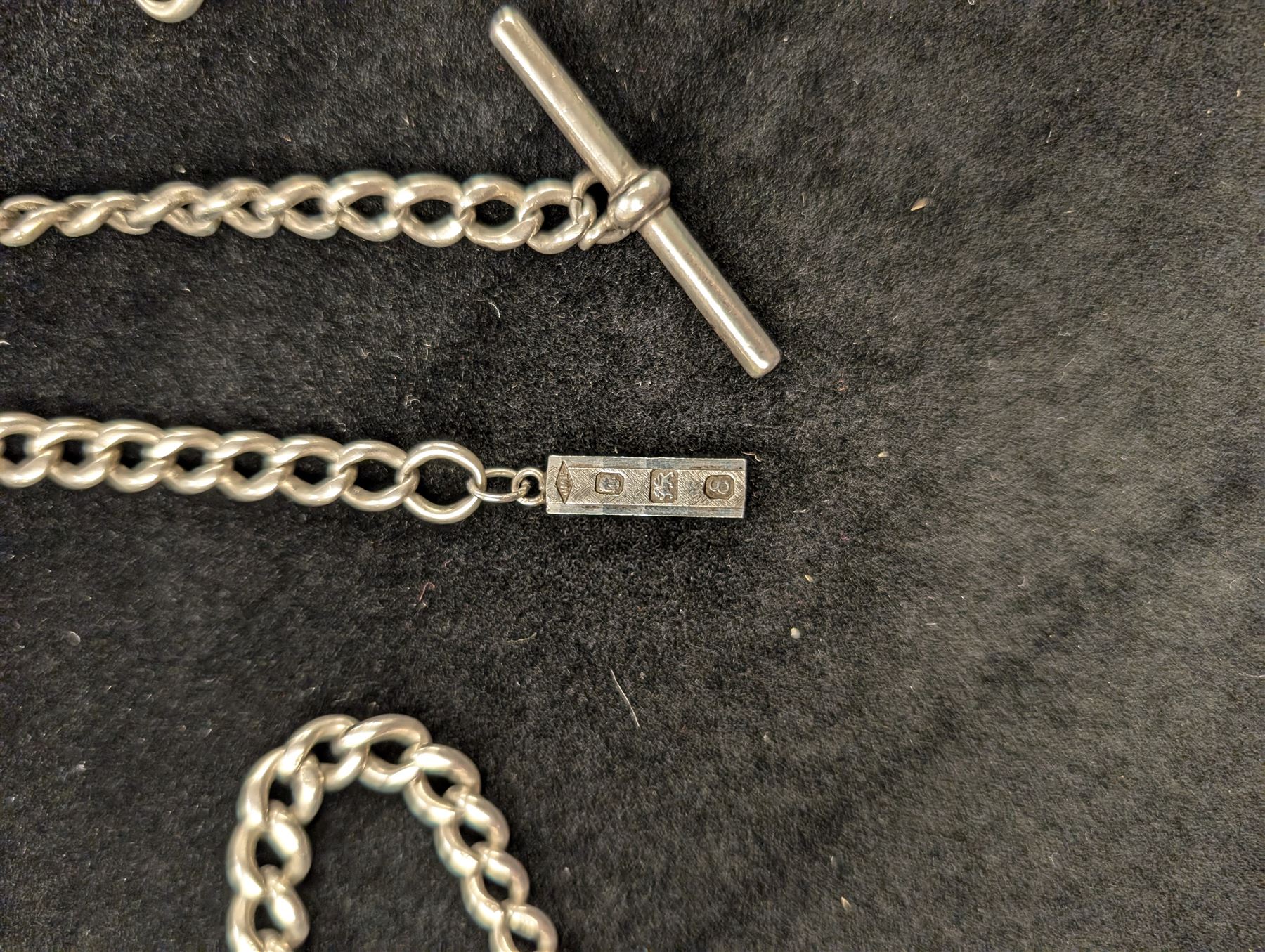 Three silver Albert chains, including one tapering example with miniature ingot pendant, tapering example with plated t-bar and one other, all stamped or hallmarked 