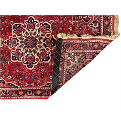 Persian Hamadan crimson ground rug, central floral pole medallion with matching spandrels, the guarded indigo border with interlaced palmettes