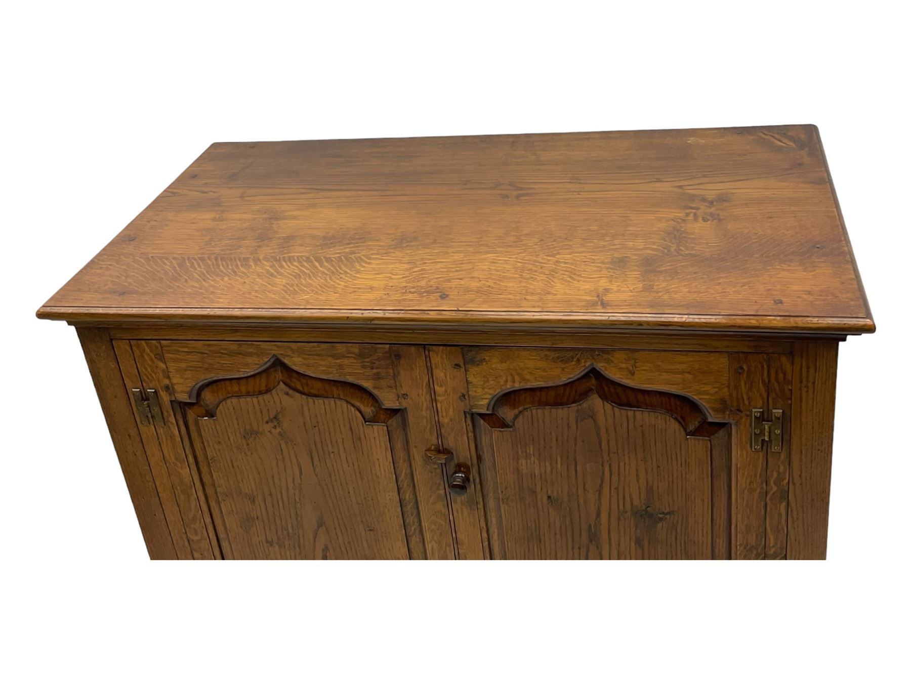 Oak drinks or media cabinet, projecting moulded cornice over two Gothic arch panelled doors on sliding tracks enclosing open storage, two drawers with brass drop handles, on bracket supports