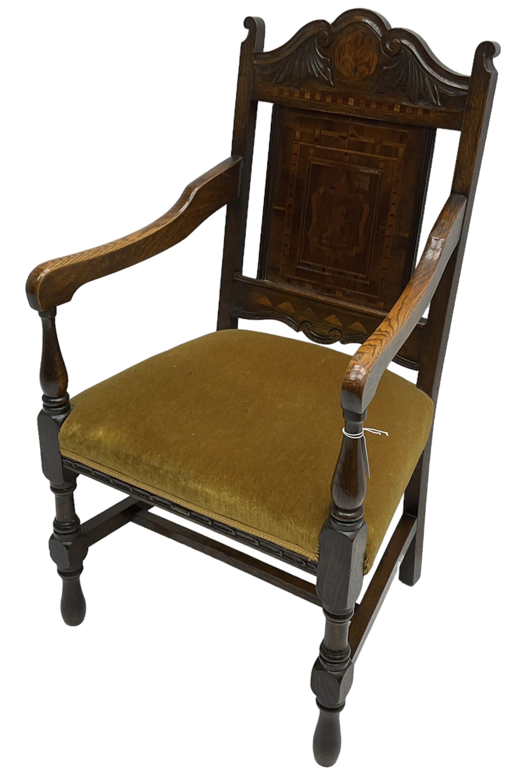 Late 19th to early 20th century oak elbow chair, the shaped cresting rail carved with scrolls and foliage, panelled back inlaid with parquetry work and central rampant lion within shield, upholstered seat, on turned supports joined by H stretchers