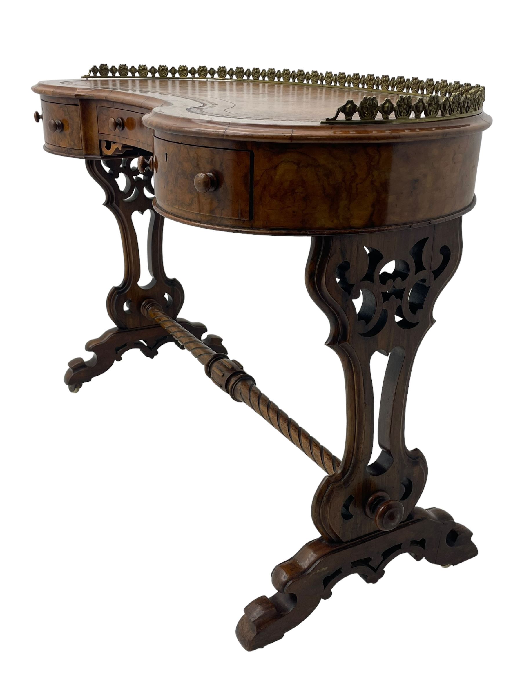 Victorian walnut kidney-shaped writing desk, moulded top with floral cast brass gallery and inset leather writing surface, fitted with three frieze drawers with turned handles, shaped and pierced end supports on raised platforms terminating to splayed feet, united by twist turned and lobe carved stretcher, brass and ceramic castors 