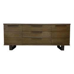 Contemporary dark oak finish sideboard, three central drawers flanked by single cupboards, on angular black finish metal supports 